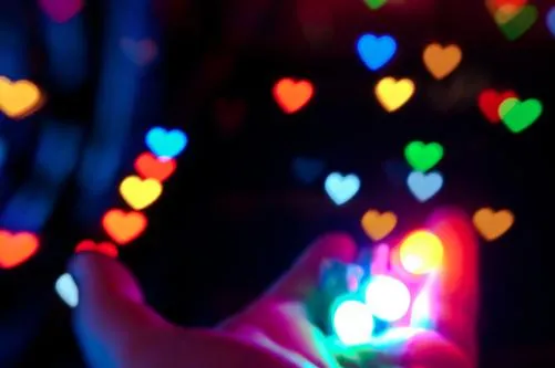 Colorful heart-shaped bokeh lights in a hand.