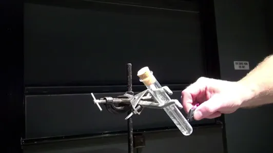 Laboratory apparatus with a test tube being held by a hand.