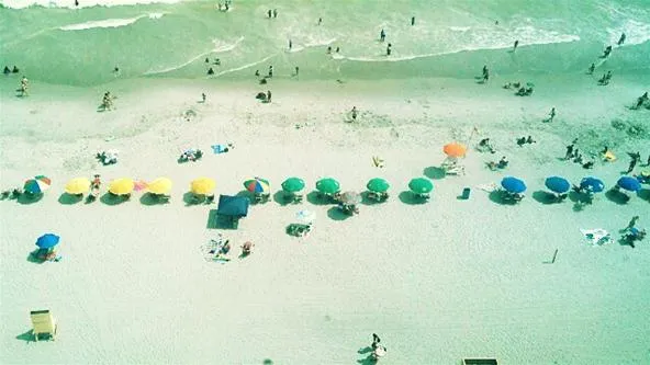 Beach scene with umbrellas and people enjoying the sun and water.