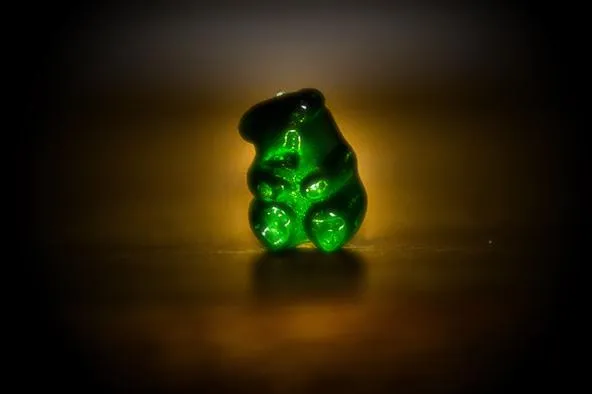 Green gummy bear candy on a dark background.