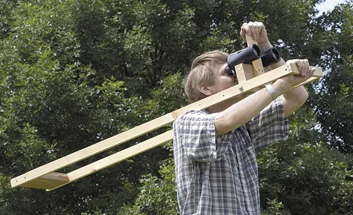 Person using a wooden instrument for measurement outdoors.