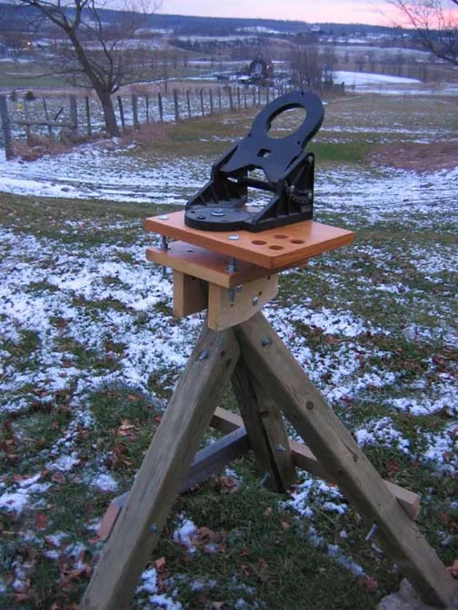 A black shoe placed on a wooden display in a snowy outdoor setting.