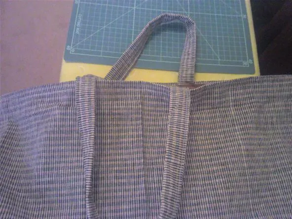 A close-up of a checkered fabric tote bag on a cutting mat.