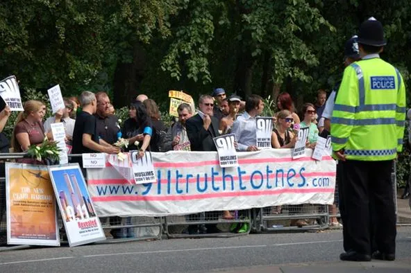 "Protesters holding banners at a demonstration with a police officer present."