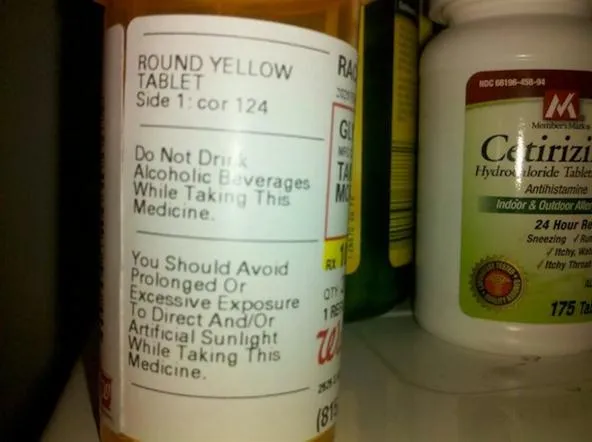 Prescription medication label for a round yellow tablet, cautioning against alcohol and sun exposure while taking the medicine.