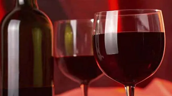 Red wine in glasses with a bottle in the background.