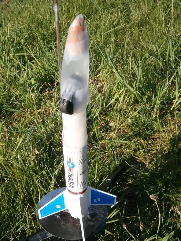 Model rocket standing on grass, ready for launch.