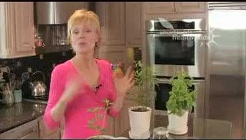 Woman demonstrating how to care for indoor plants in a kitchen setting.