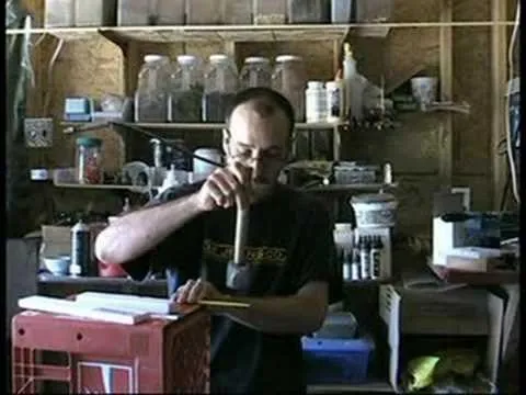 Man working in a workshop, using a mallet on a wooden object.