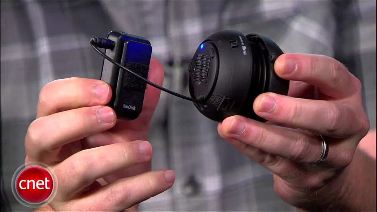 Hand holding a white device with a blue element, possibly a gadget or tool.