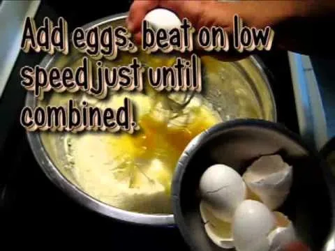 Mixing eggs into a batter with a whisk.