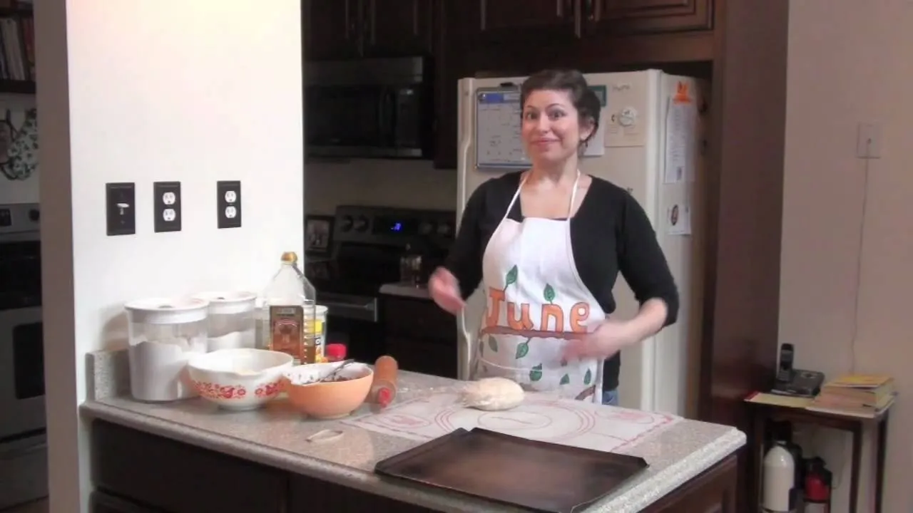 Person preparing pizza with toppings on a wooden countertop.