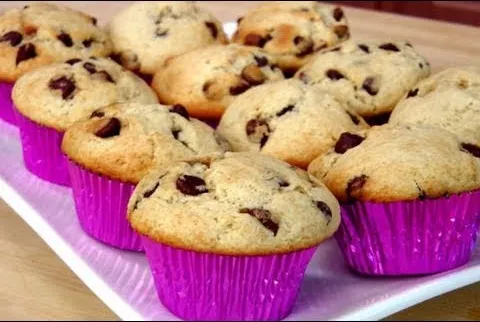 Chocolate chip muffins in pink wrappers on a white plate.