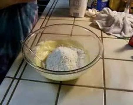 Mixing ingredients in a glass bowl on a tiled countertop.