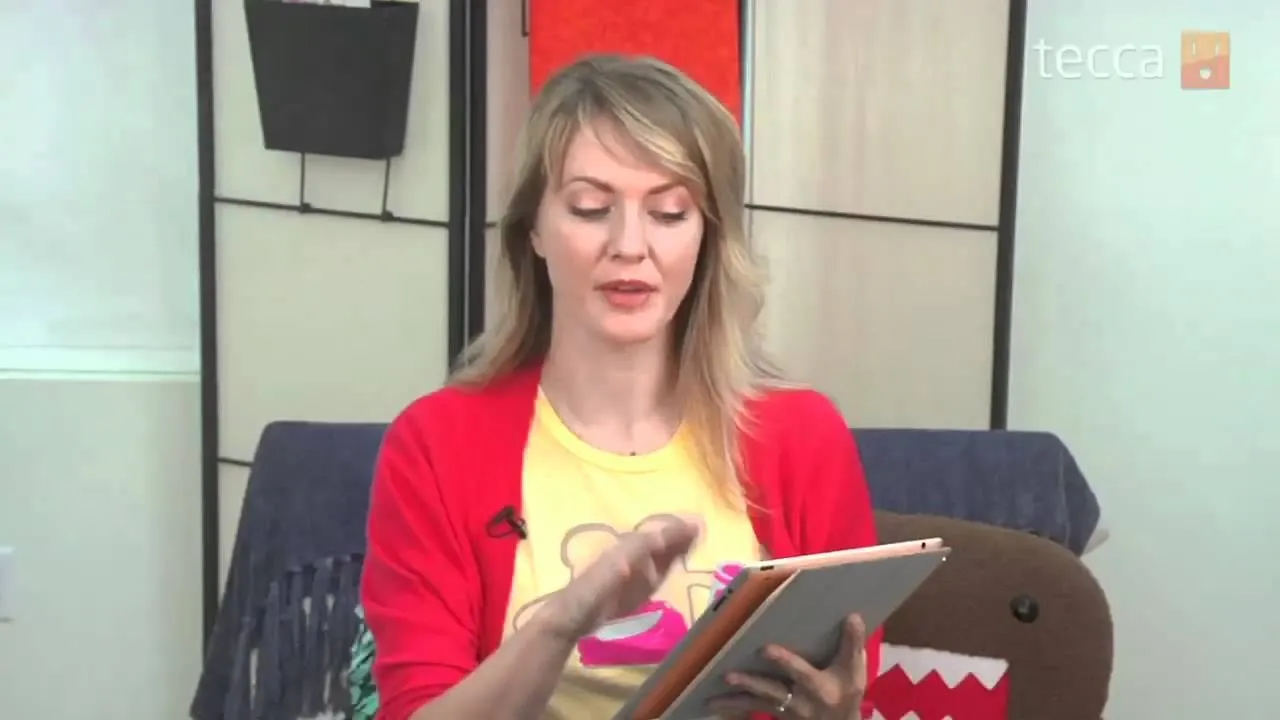 Woman sitting on a couch holding a tablet.