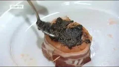 Gourmet dish being prepared with a spoonful of dark topping on a savory base.