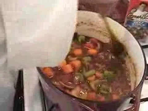 A pot of stew with vegetables being served.