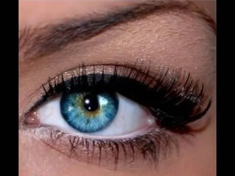 Close-up of a woman's eye with blue iris and long eyelashes.