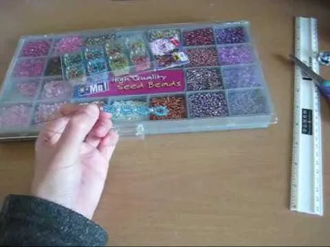 A hand reaching for colorful beads in a storage container.
