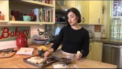 Woman preparing baked goods in a kitchen.
