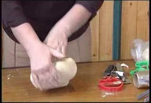 Kneading dough on a wooden surface with kitchen utensils nearby.