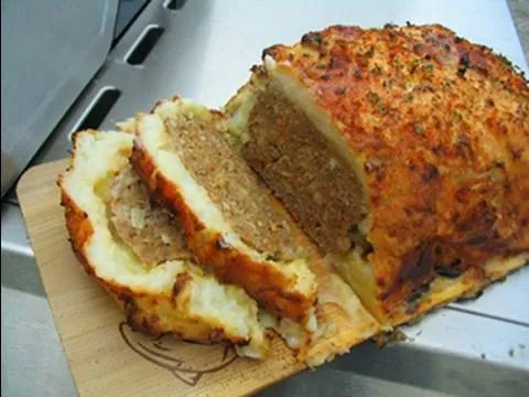 Baked meatloaf with a golden crust, sliced and served.