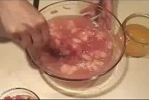 Preparation of a fruit salad in a glass bowl.