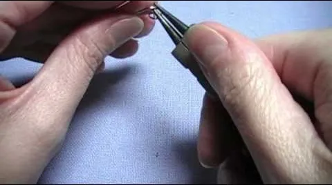 Person using pliers to manipulate a small object.