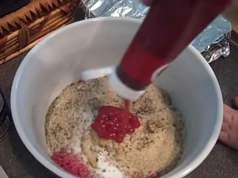 Ketchup being added to a bowl of mixed ingredients.