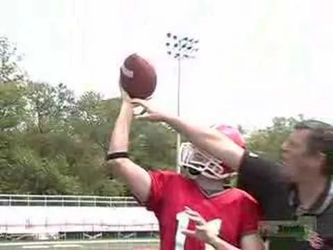 A football player throwing a football with a coach's guidance.