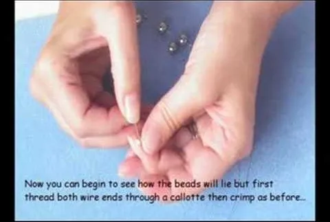 Hands threading beads onto a wire with a blue background.