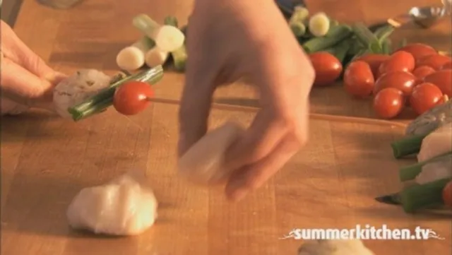 Hand picking garlic cloves on a wooden kitchen counter with fresh vegetables.