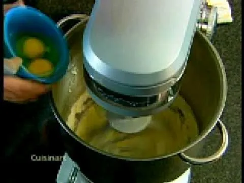 Mixing batter in a stand mixer with eggs being added.