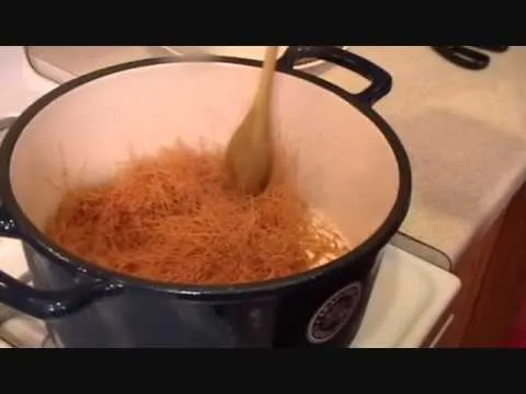Stirring cooked vermicelli pasta in a pot.
