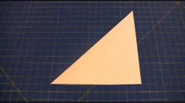 Triangle paper cutout on a blue cutting mat.