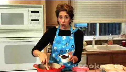 Woman cooking in a kitchen, mixing ingredients in a pot.