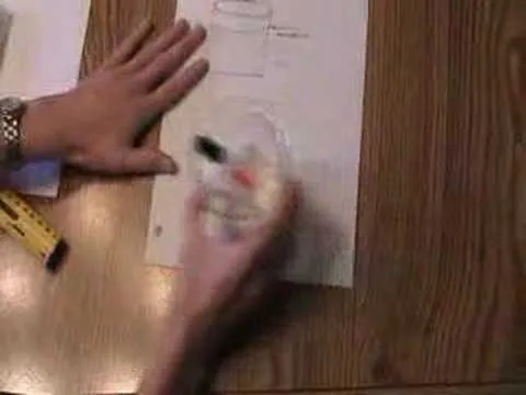 A person applying white correction fluid to paper on a wooden table.