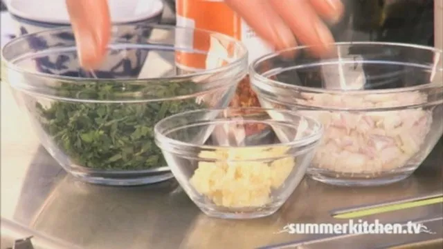 Ingredients in glass bowls for a cooking preparation, including chopped herbs, ginger, and garlic.
