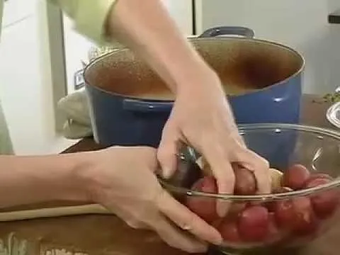 Hands preparing red potatoes in a bowl with a pot in the background.