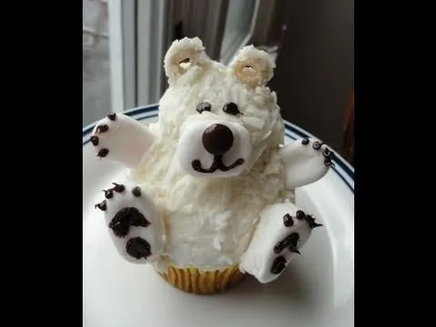 Bear-shaped cupcake decorated with white frosting and candy features.