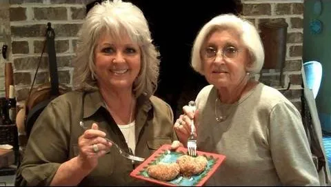 Two women holding a plate of cookies, smiling at the camera.