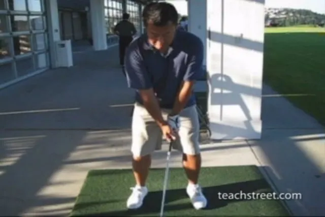 Golfer preparing to swing at a driving range.
