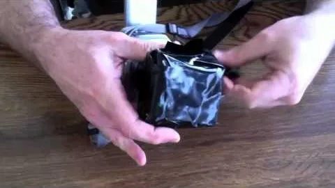 A person holding a small black object wrapped in plastic.