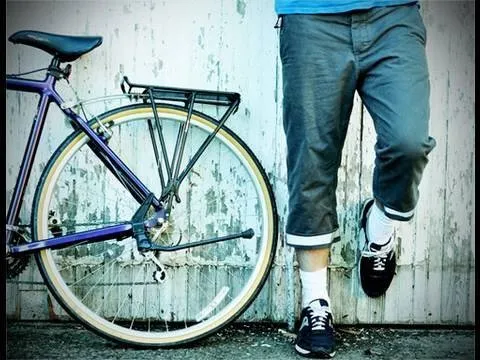 Person leaning against a wall next to a bicycle.