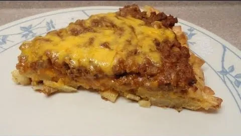 Person preparing pizza with toppings on a wooden countertop.