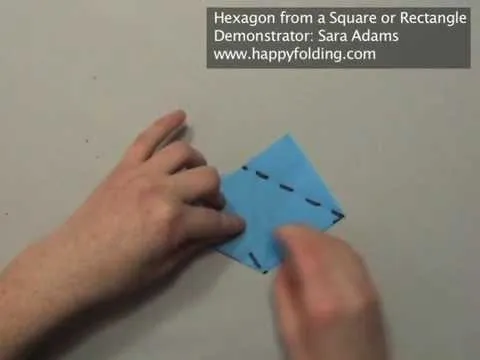 Hand folding a blue piece of paper into a hexagon shape.