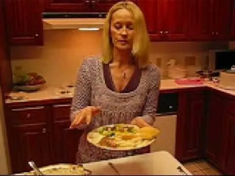 Woman holding a plate of food in a kitchen.