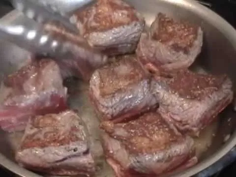 Searing beef cubes in a skillet.