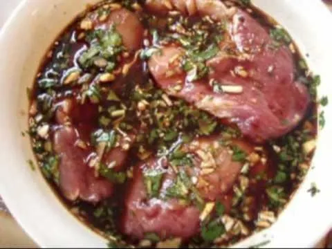 Marinated meat with herbs and spices in a bowl.