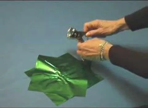Person using scissors to cut green wrapping paper.